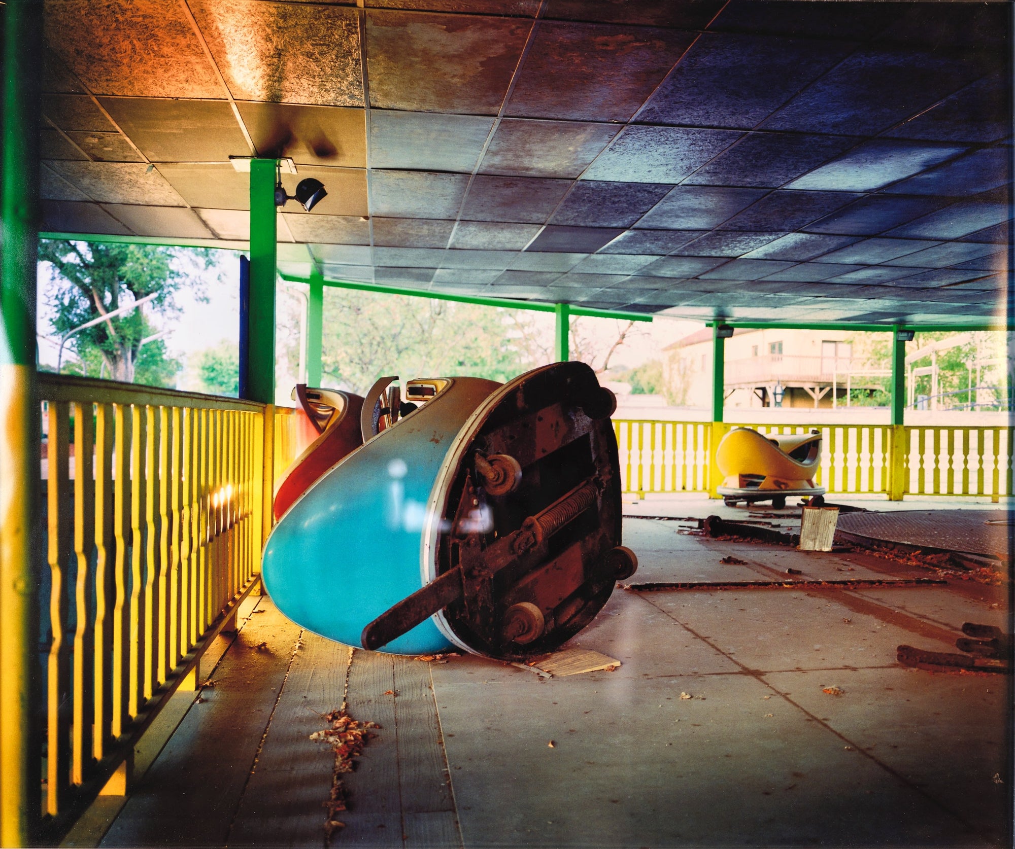 Suzi Poling, Bumper Car, photograph, pale blue bumper car overturned in abandoned amusement park